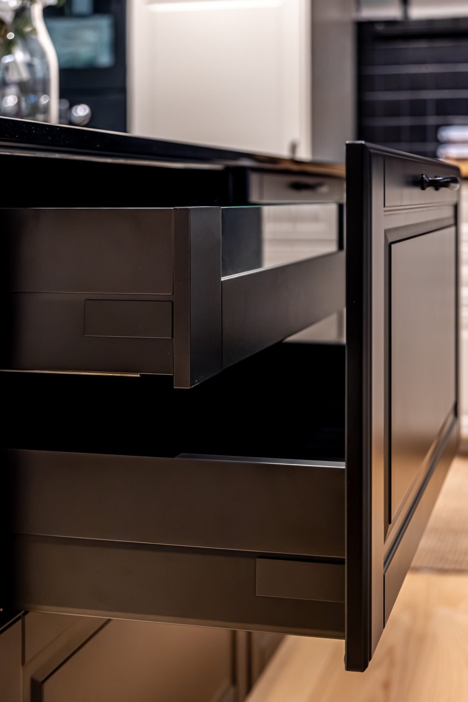 Low angle focus on a matte pullout drawer and clean lines under a dark countertop. Declutter smart organization concept with modern interior aesthetic.
